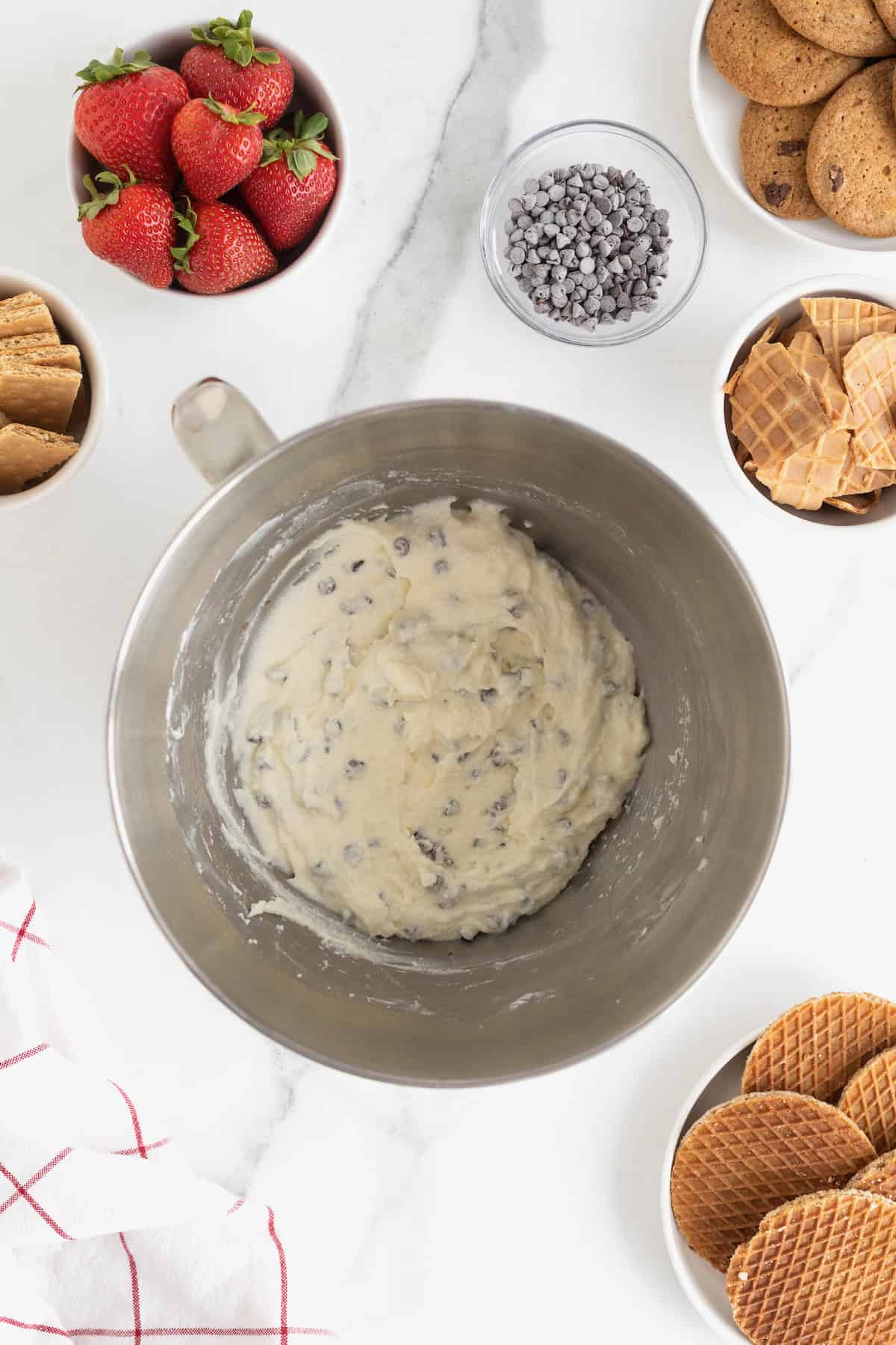 A stainless steel mixing bowl with chocolate chip cannoli dip mixed together.