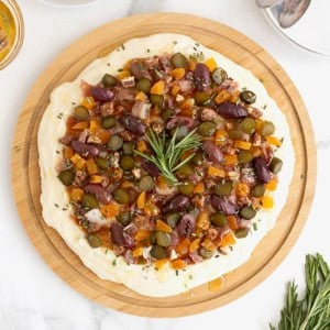 A round wood food board spread with charcuterie dip.