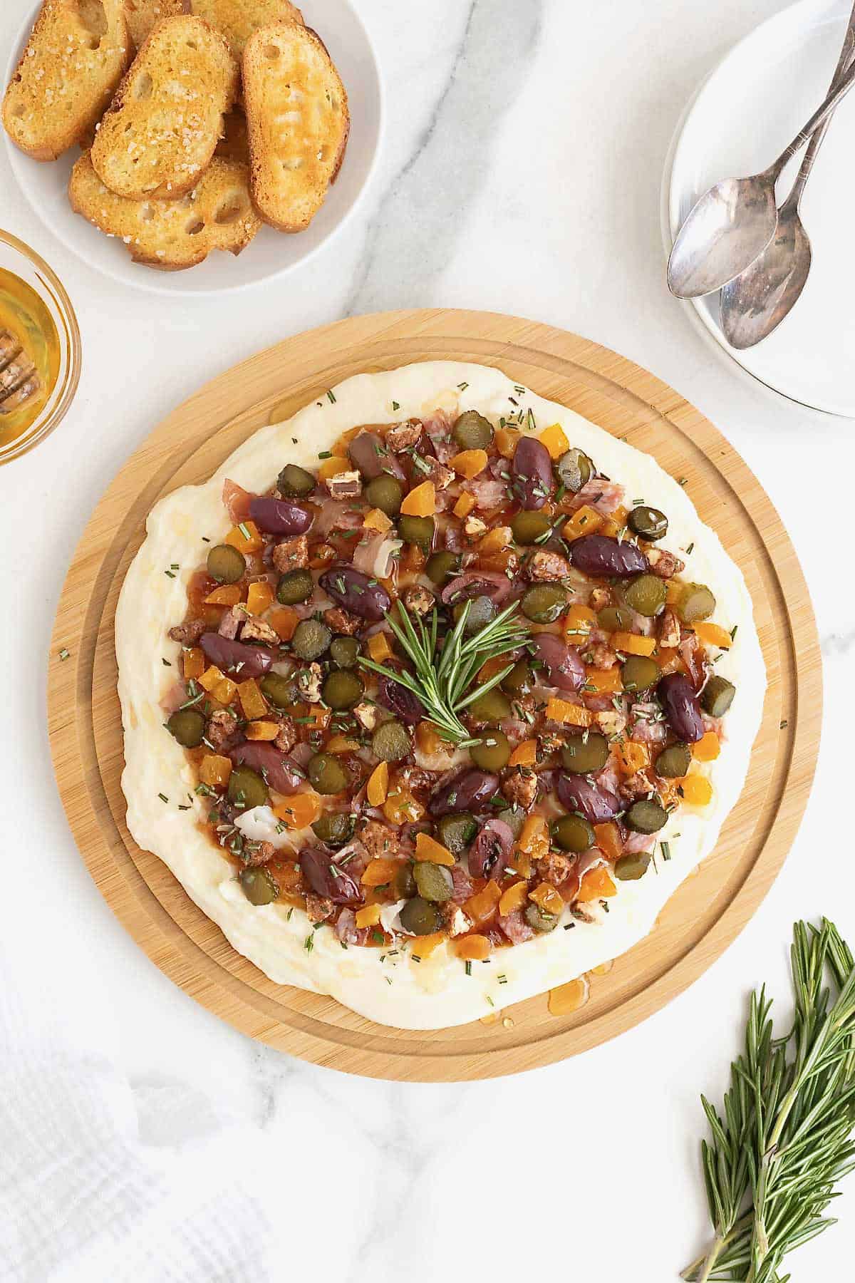A round wood food board spread with charcuterie dip.