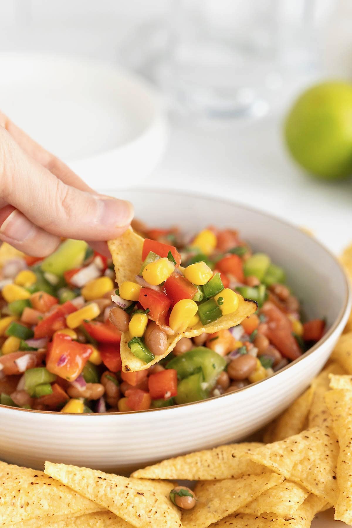 Baked bean cowboy caviar on a corn tortilla chip above a bowl of the dip.
