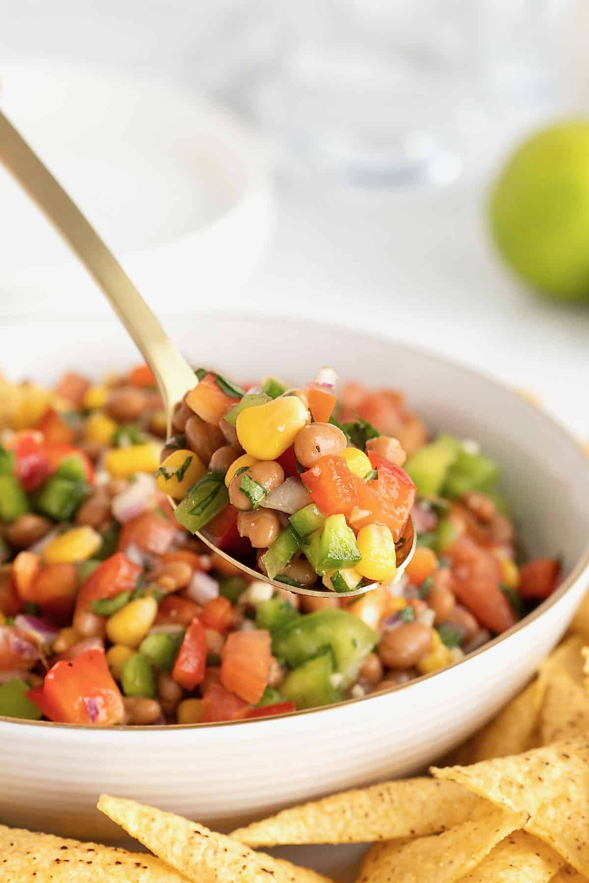 Baked beans cowboy caviar on a spoon over a bowl.