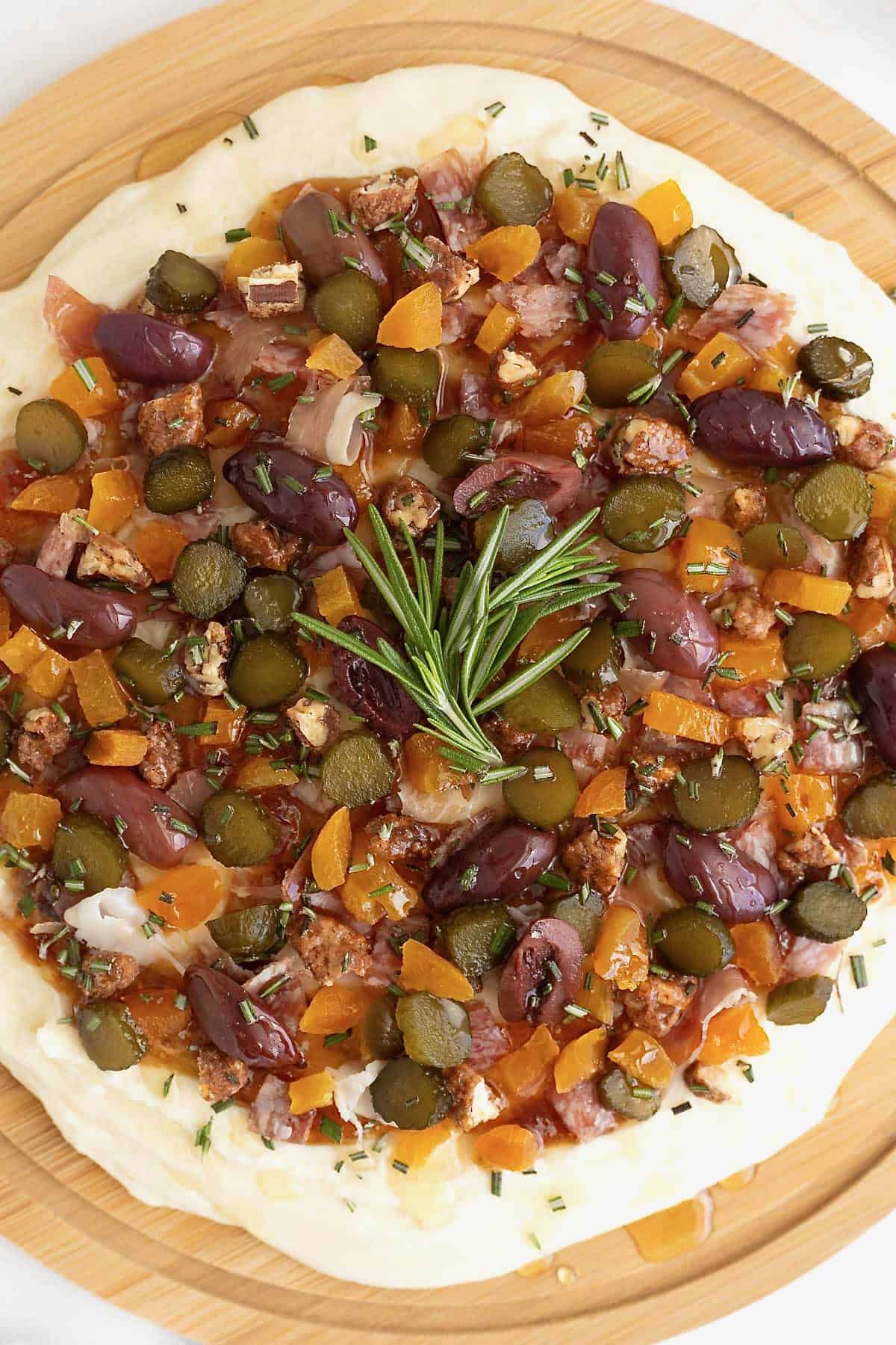 A round wood food board spread with charcuterie dip.