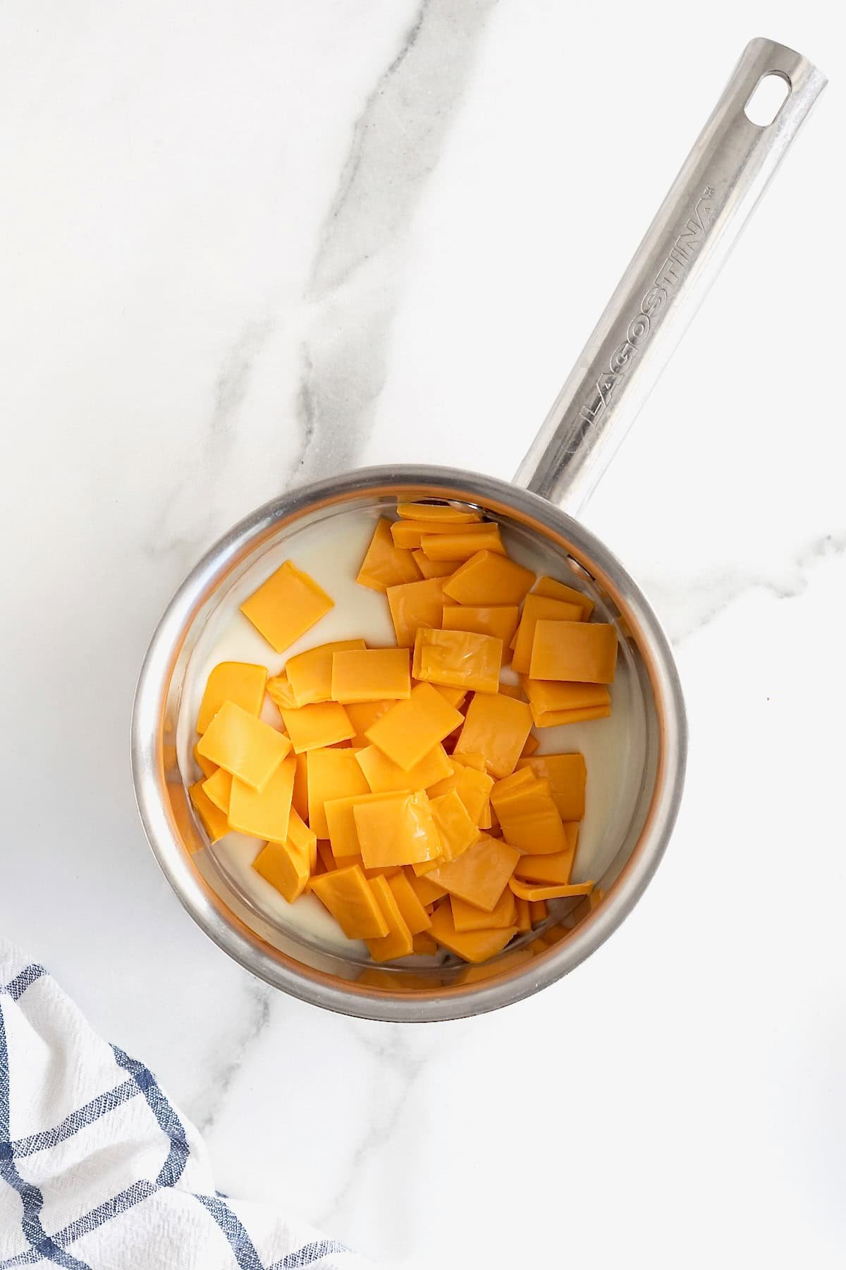 Squares of American cheese added to a metal sauce pan.