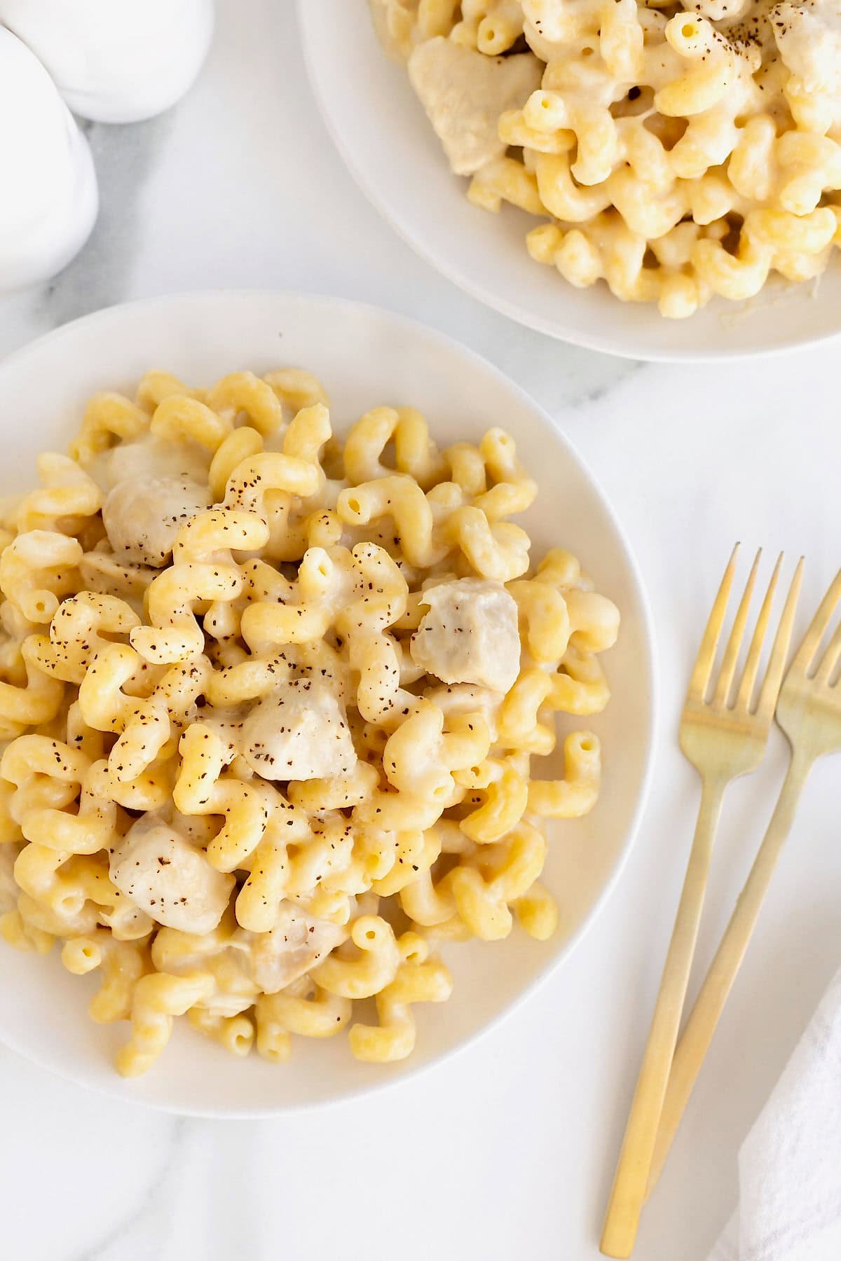 A large white dinner plate of chicken Alfredo pasta.