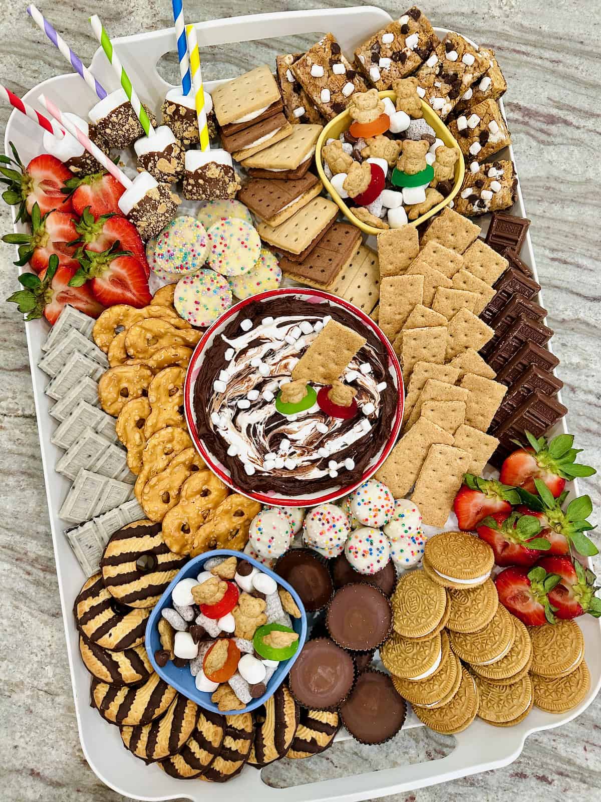 A white plastic tray filled with s'mores treats on a dark grey marble counter.