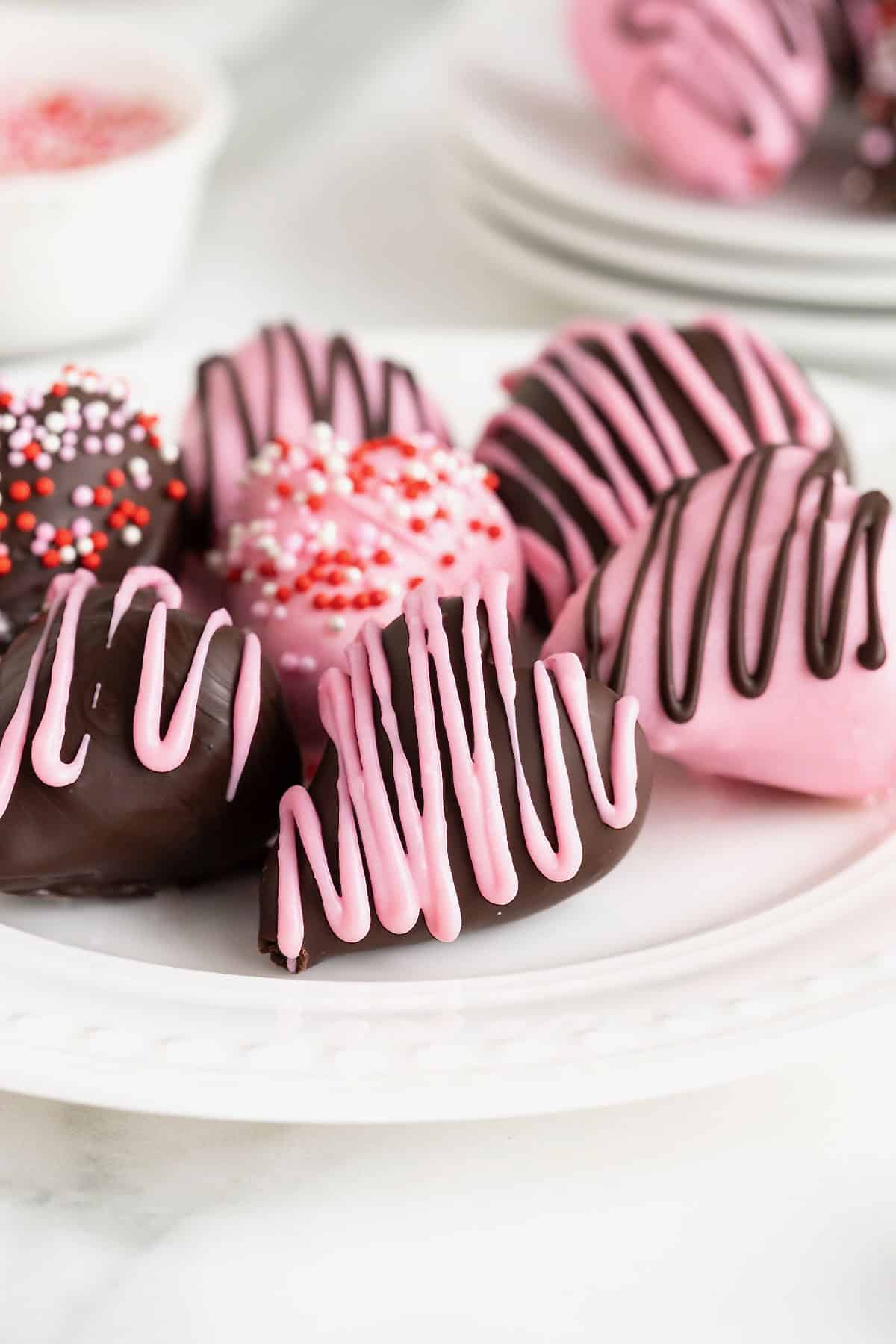 Seven heart-shaped chocolate covered strawberries on a white plate with bead detail.