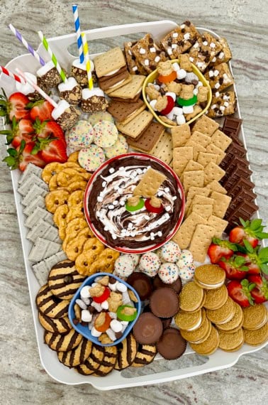 A white plastic tray filled with s'mores treats on a dark grey marble counter.