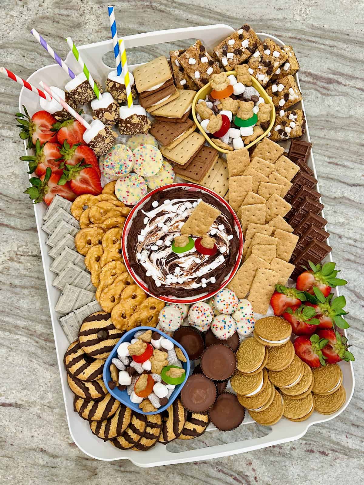 A white plastic tray filled with s'mores treats on a dark grey marble counter.