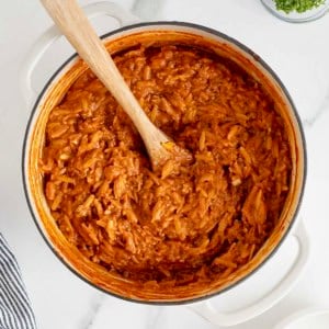 A white Dutch oven of sloppy Joe orzo on a white marble counter.