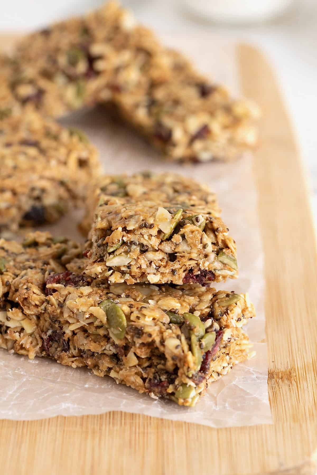 Power bars stack on a parchment lined cutting board. The top bar has a bite out of it.