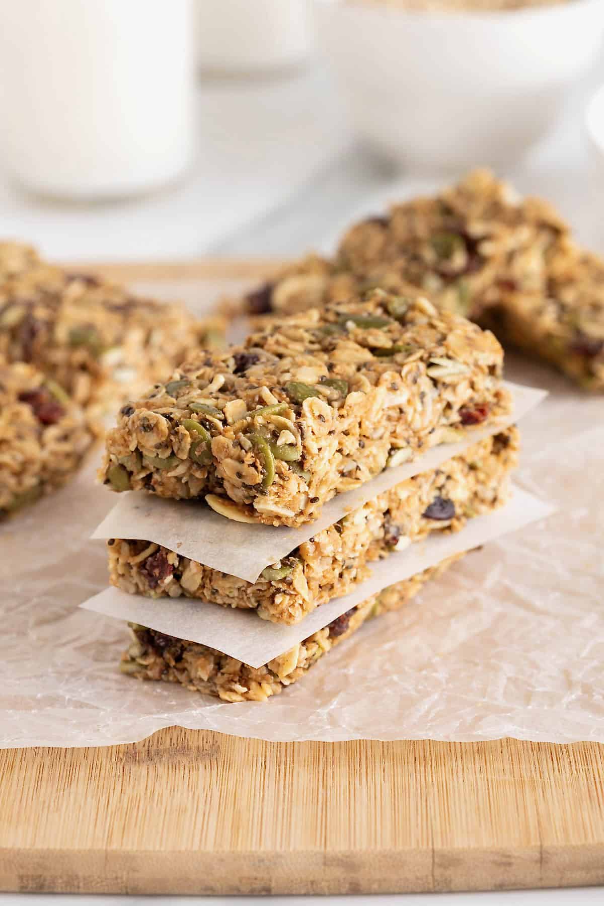 Three power bars stacked with parchment between them on a parchment lined wooden cutting board.