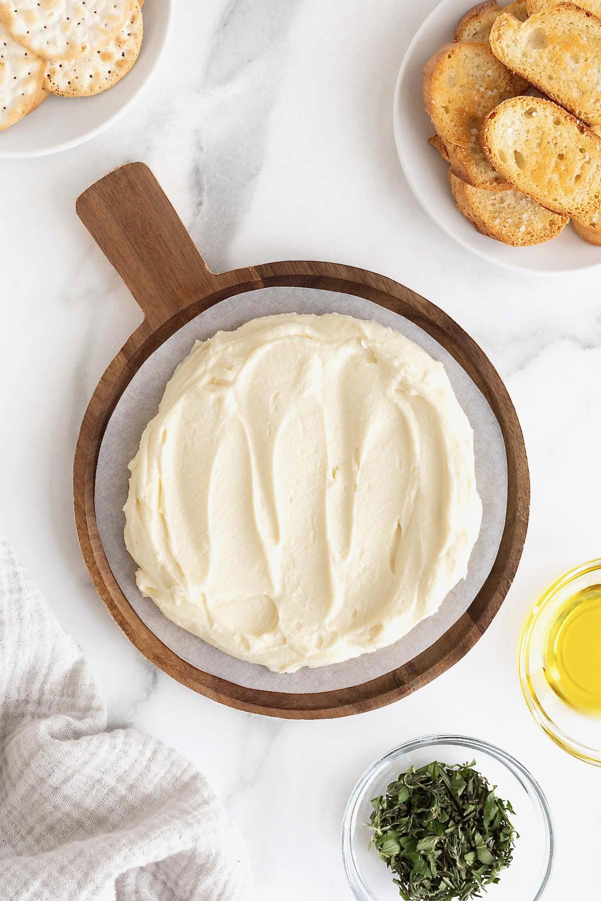 Whipped brie spread on a wooden serving plate on a white marble counter.