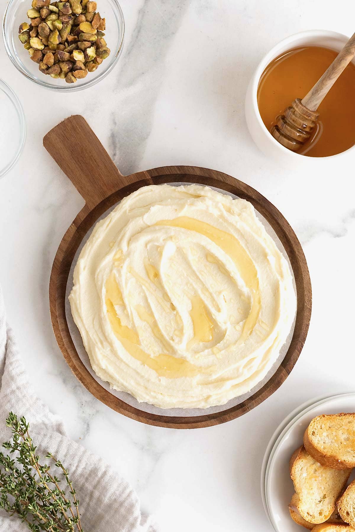 Honey drizzled on whipped brie on a wooden serving platter with a handle.