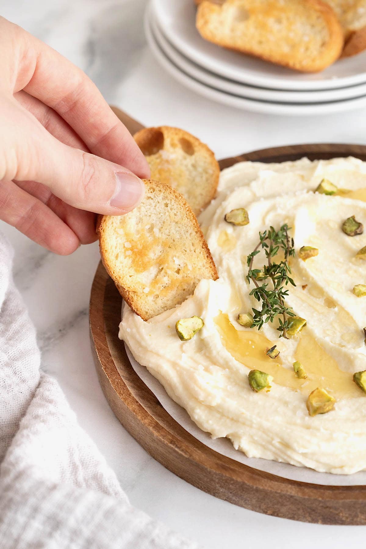 Crostini being dipped in sweet whipped brie dip.