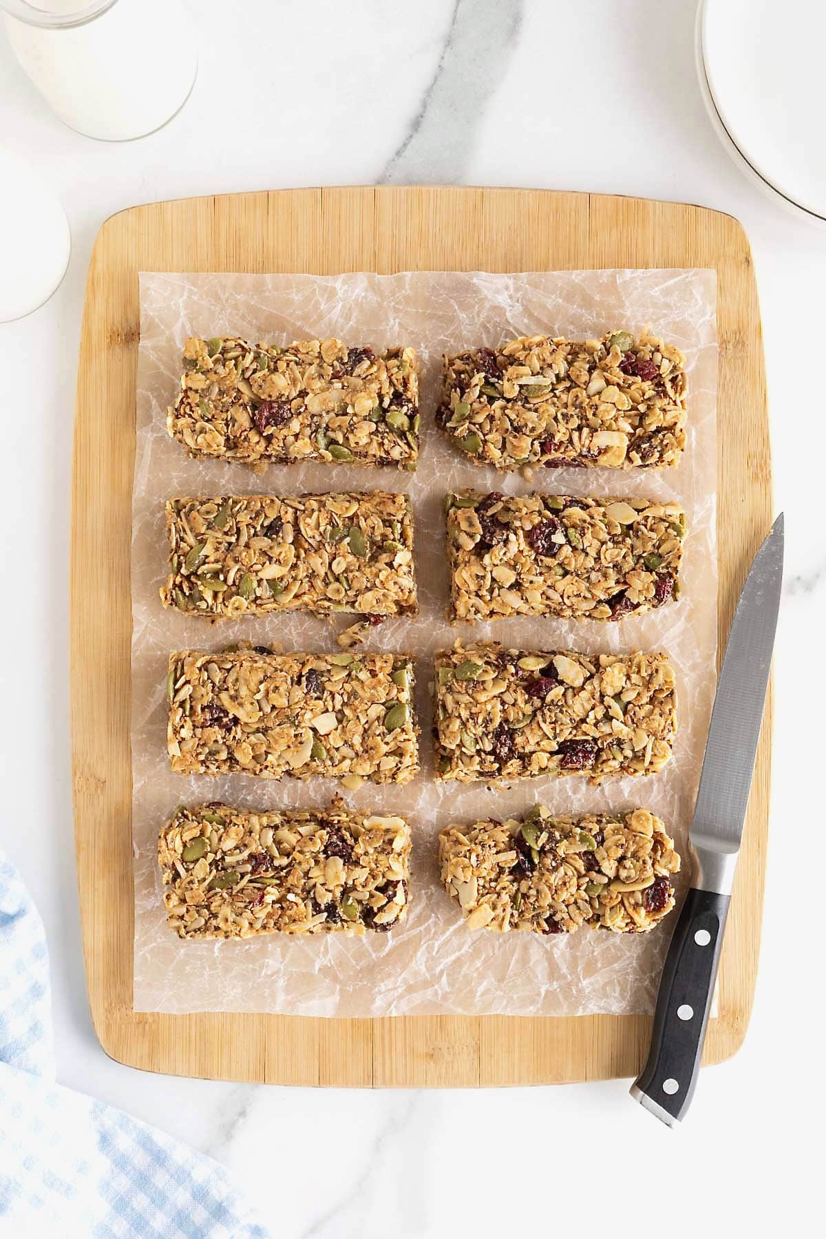 Eight power bars on a parchment lined wooden cutting board next to a small knife.