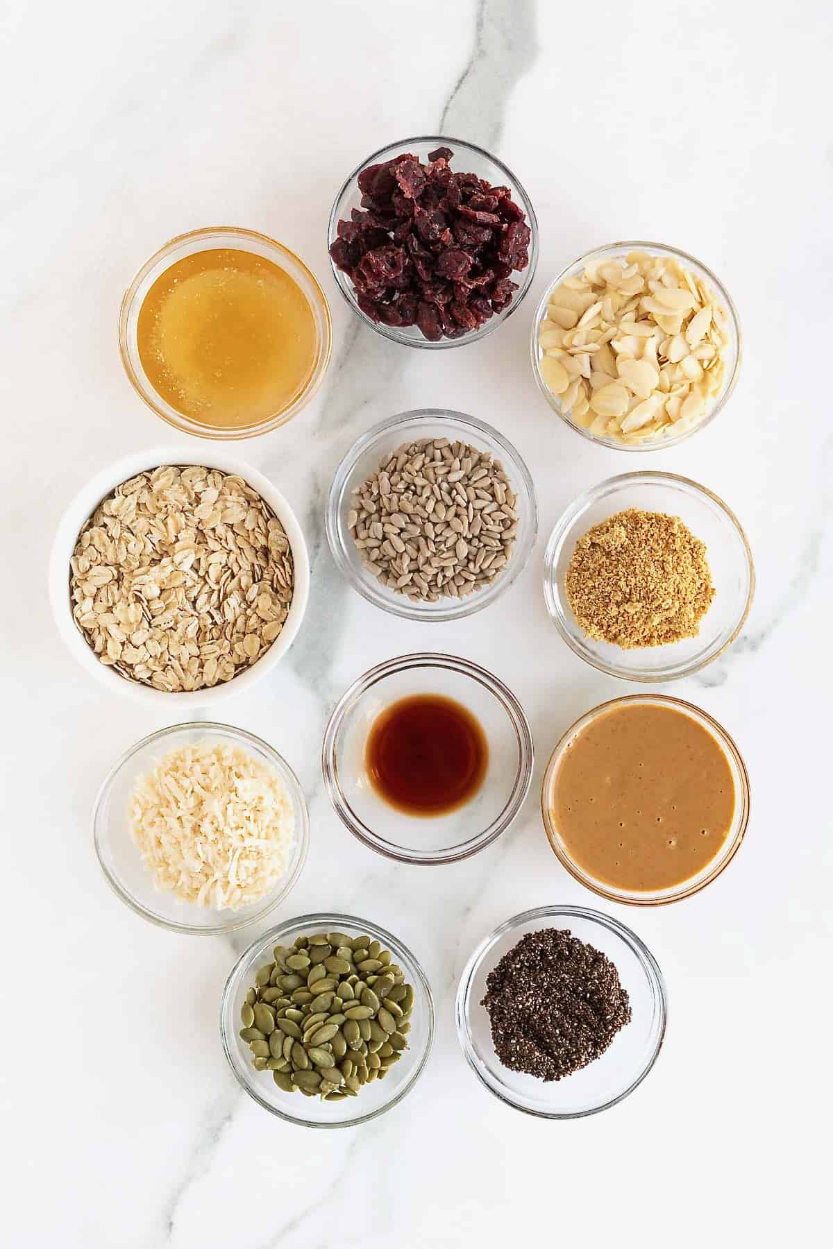 Ingredients to make No-Bake Power bars in small glass dishes on a white marble counter.