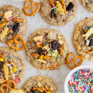Kitchen sink cookies on a parchment lined surface next to a small bowl of confetti sprinkles.