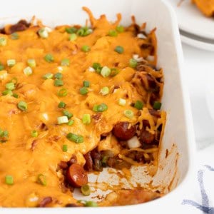 A rectangular white casserole dish of chili cheese dog casserole.