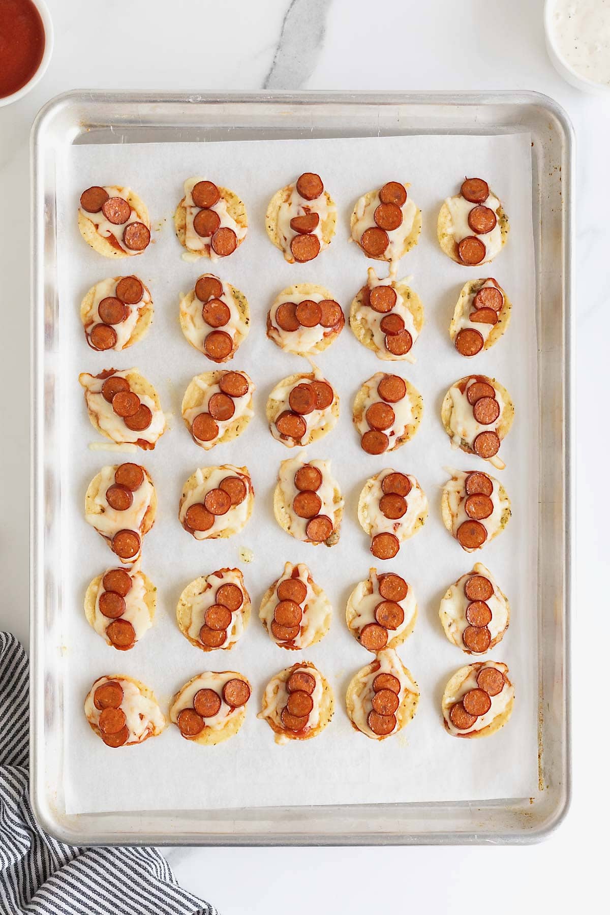 Pizza taco bites on a parchment lined baking sheet.