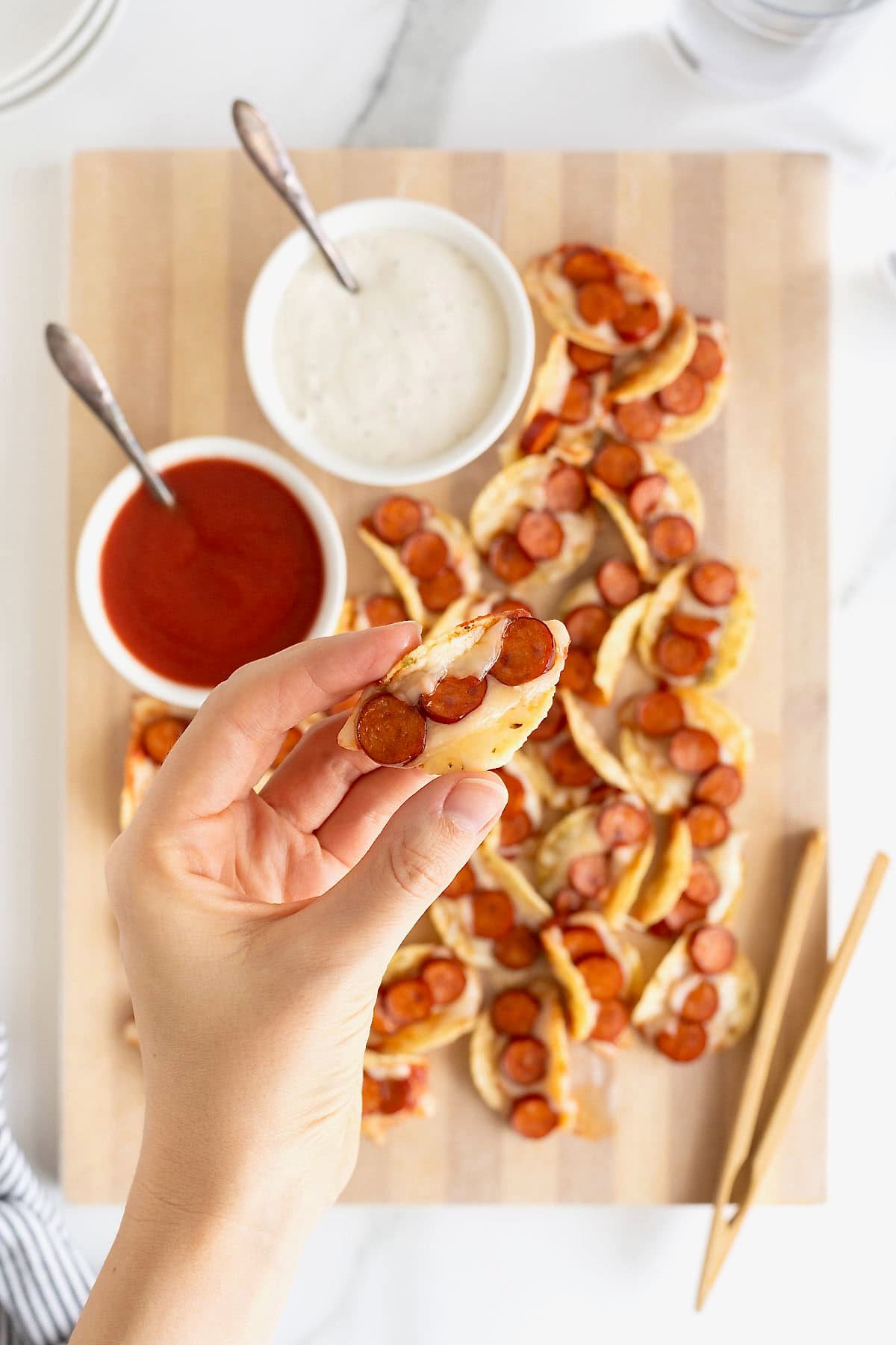 A hand holding a pizza taco bite.