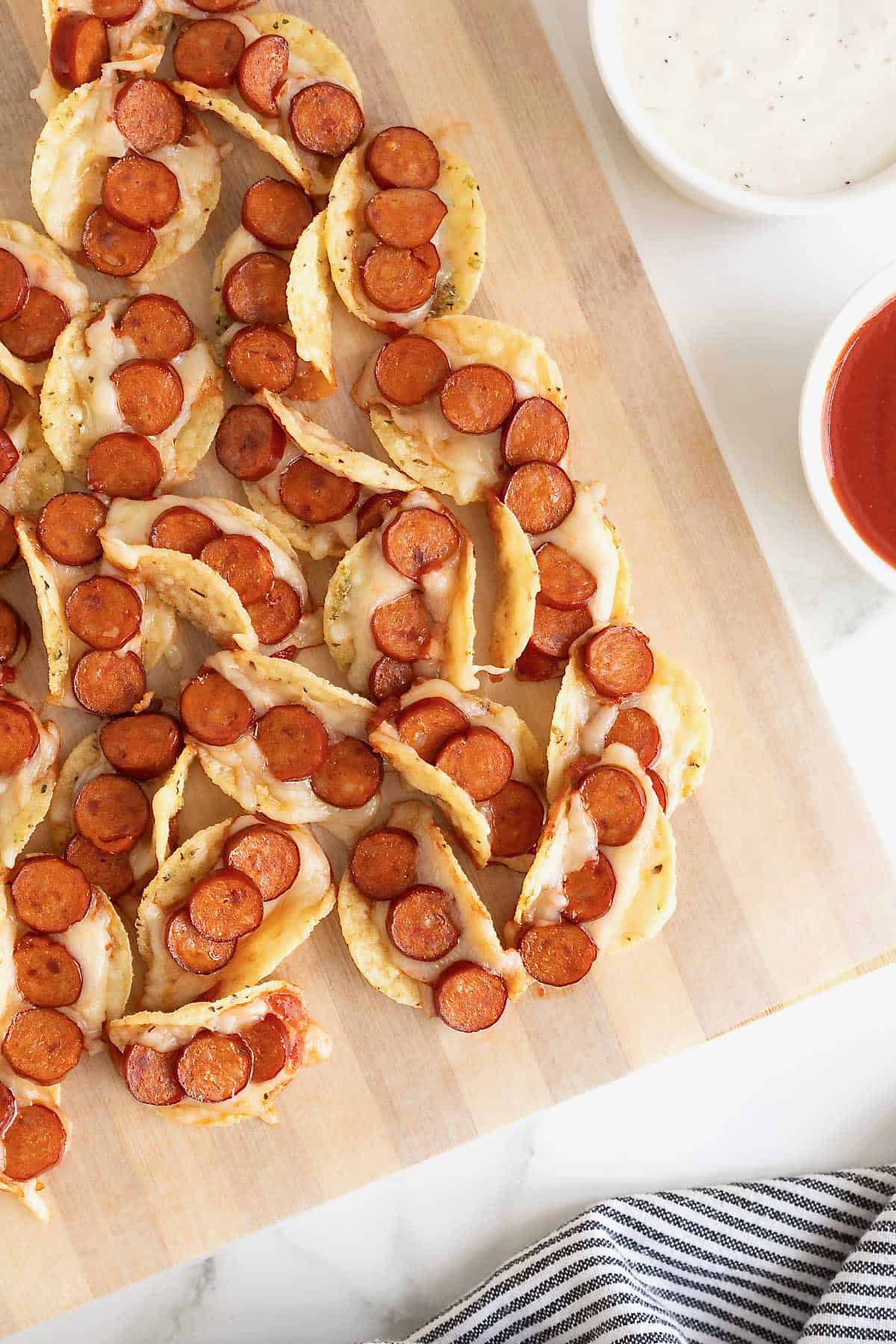 A pile of pizza taco bites on a parchment lined wooden cutting board.