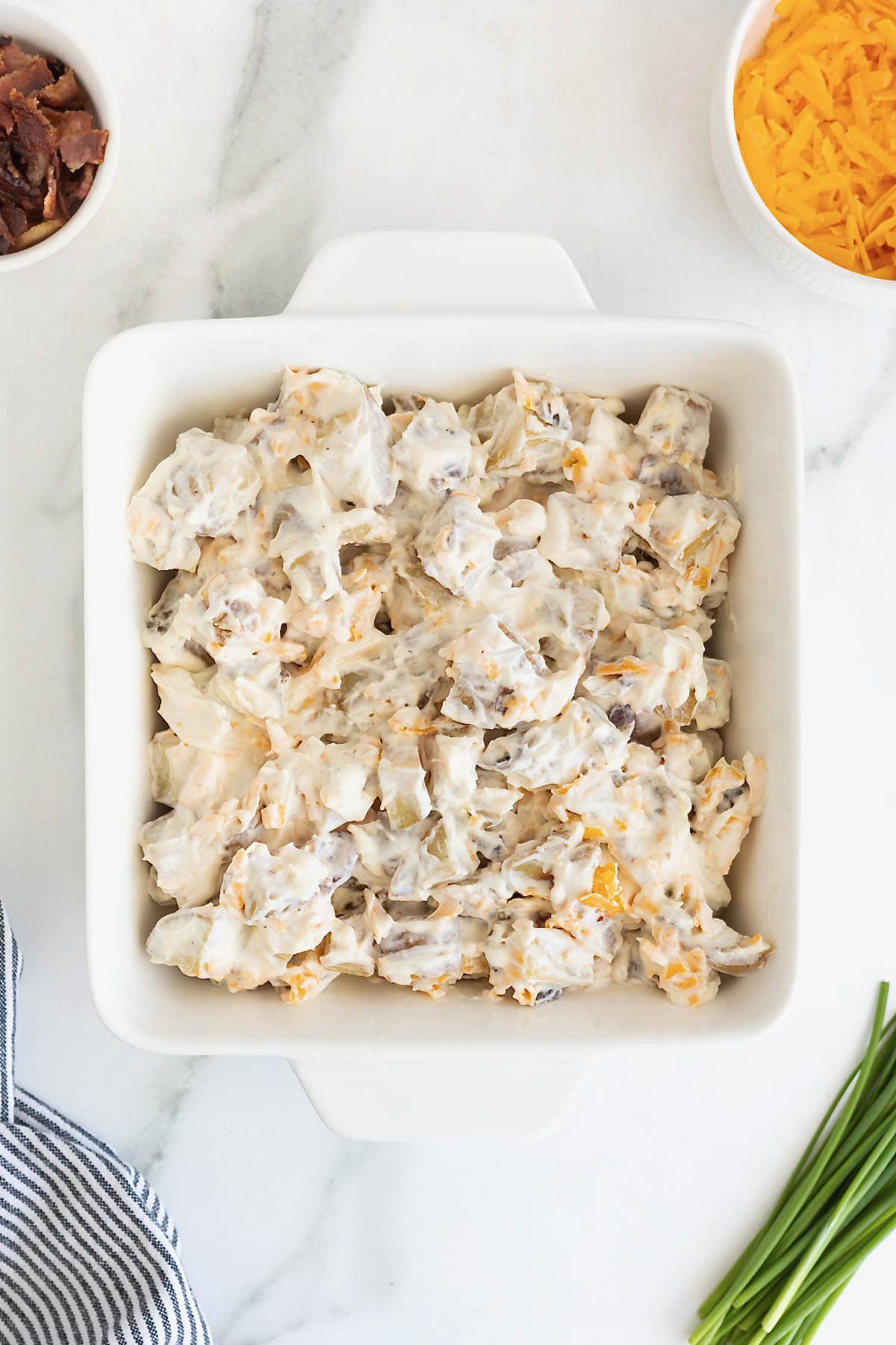 Potatoes in a sour cream sauce in a square white baking dish.