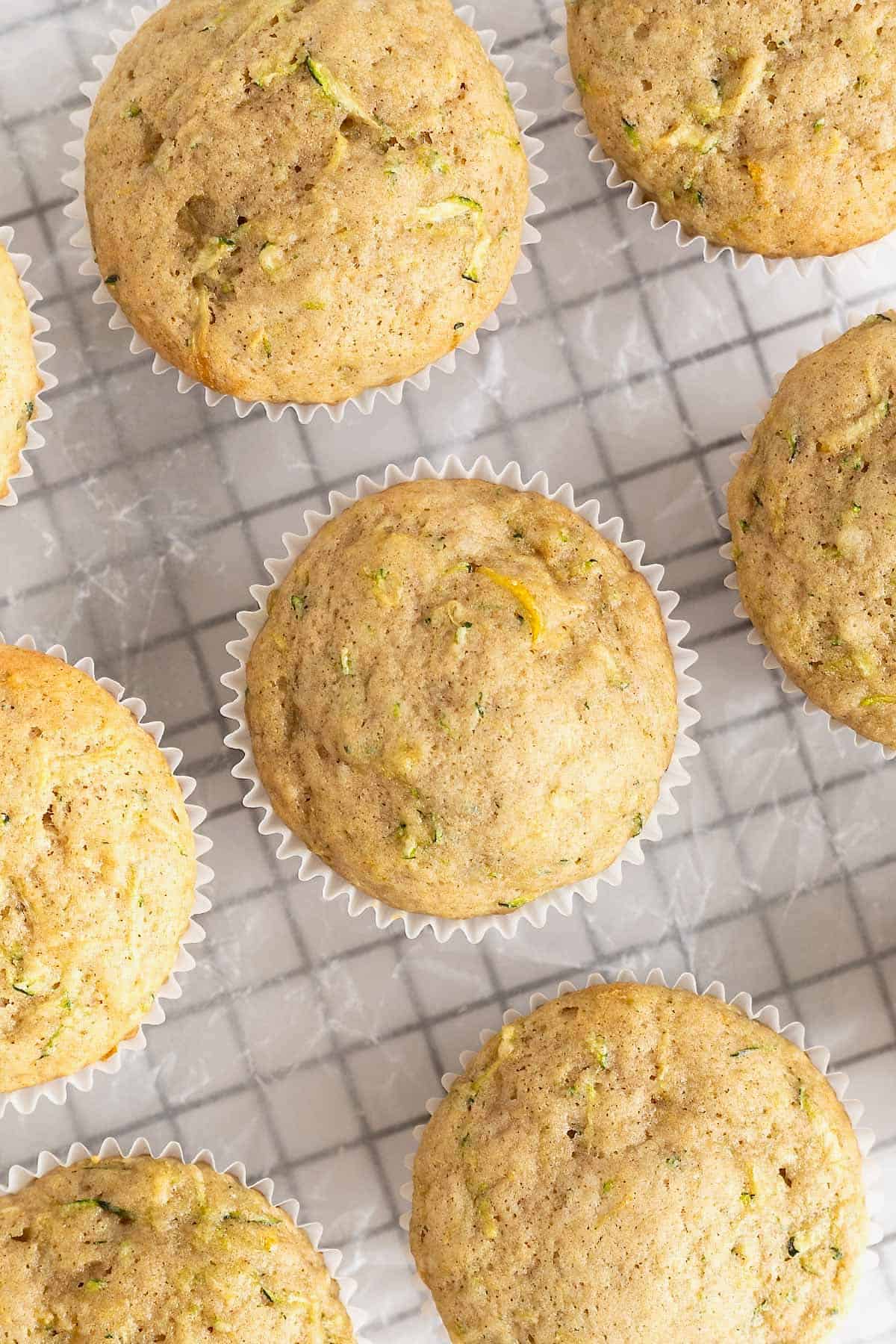 Zucchini muffins on a parchment lined wire cooling rack.
