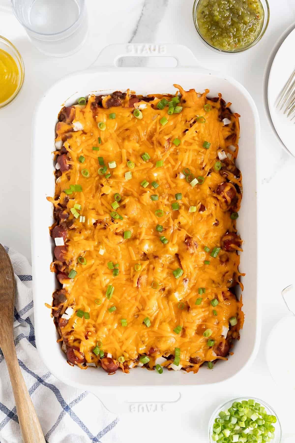A white casserole dish of chili cheese dog casserole.