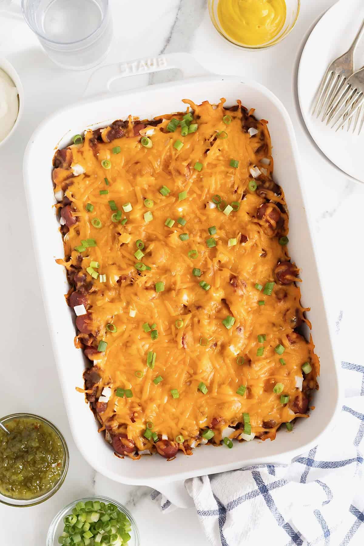 A white casserole dish of chili cheese dog casserole.