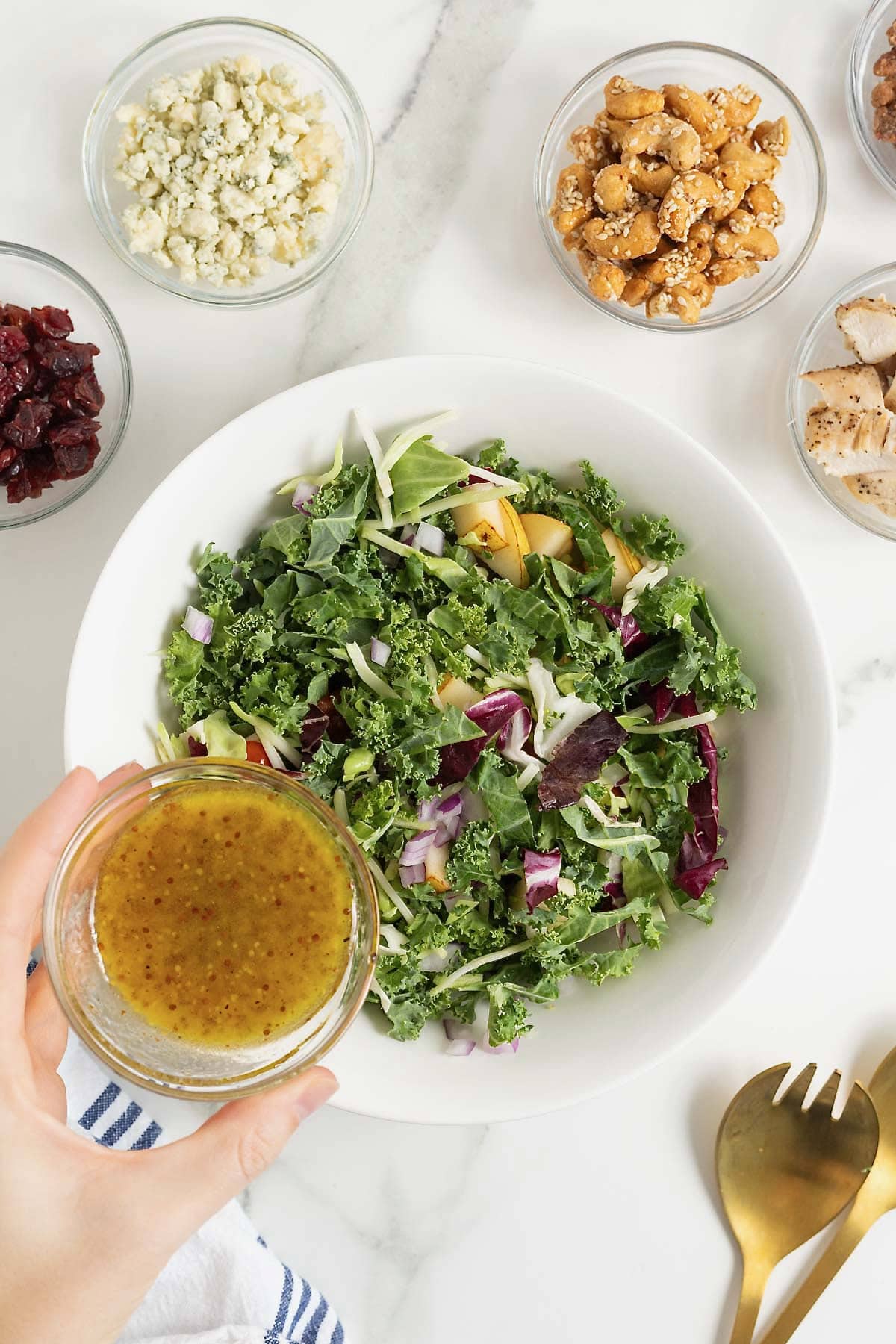 Champagne vinaigrette being poured from a small glass carafe onto a green salad.