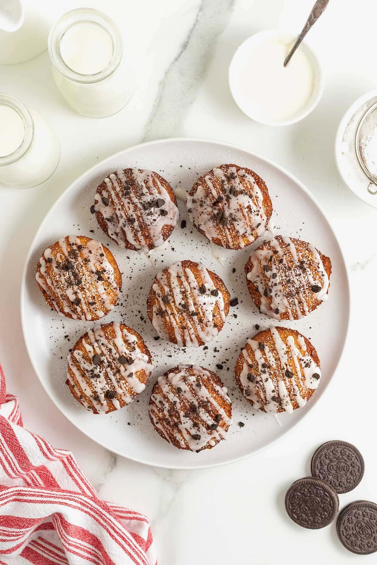 A white rimmed plate filled with 8 cinnamon roll fried Oreos. 