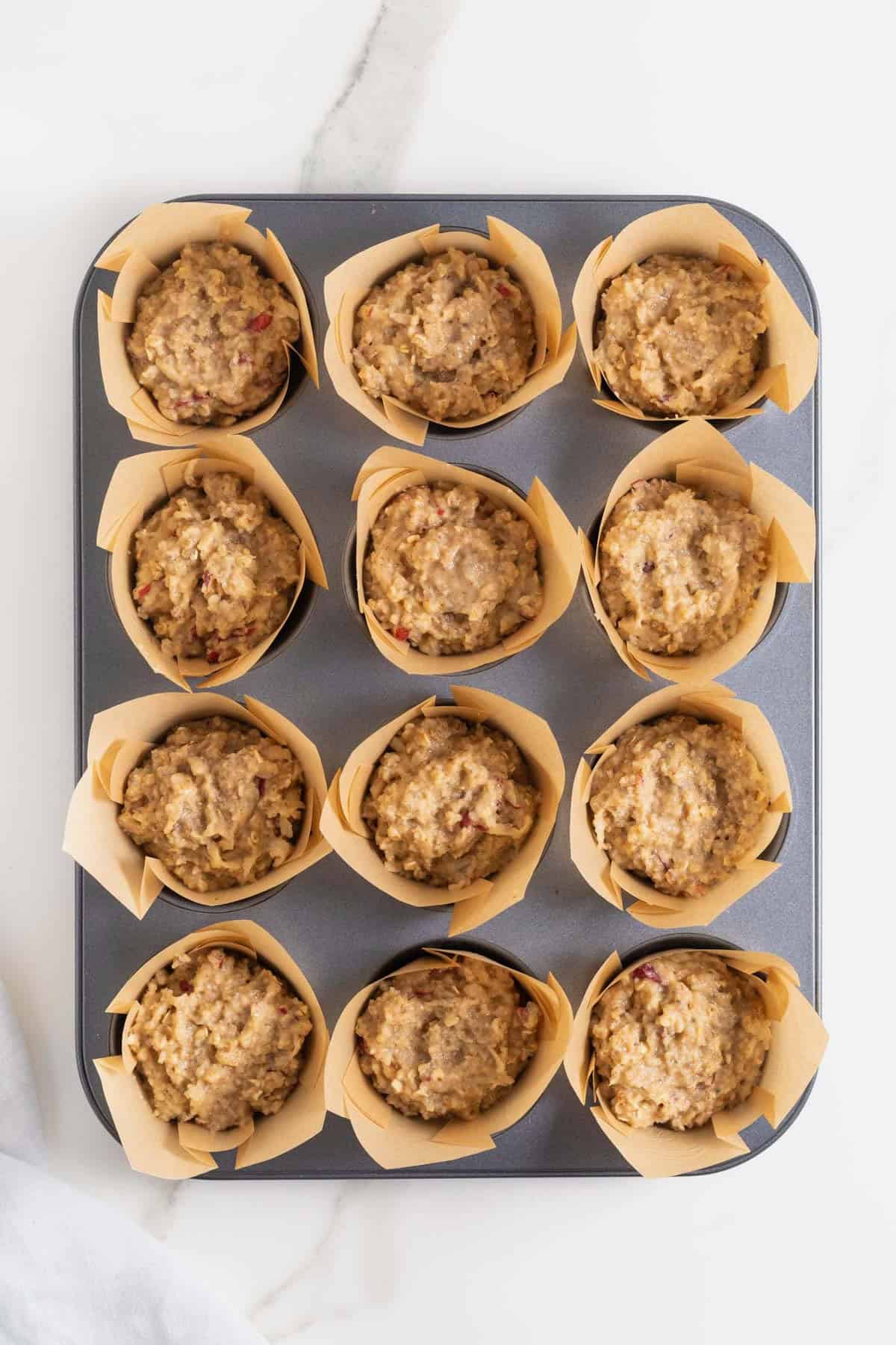 Superfood batter in a muffin tin with brown paper liners.