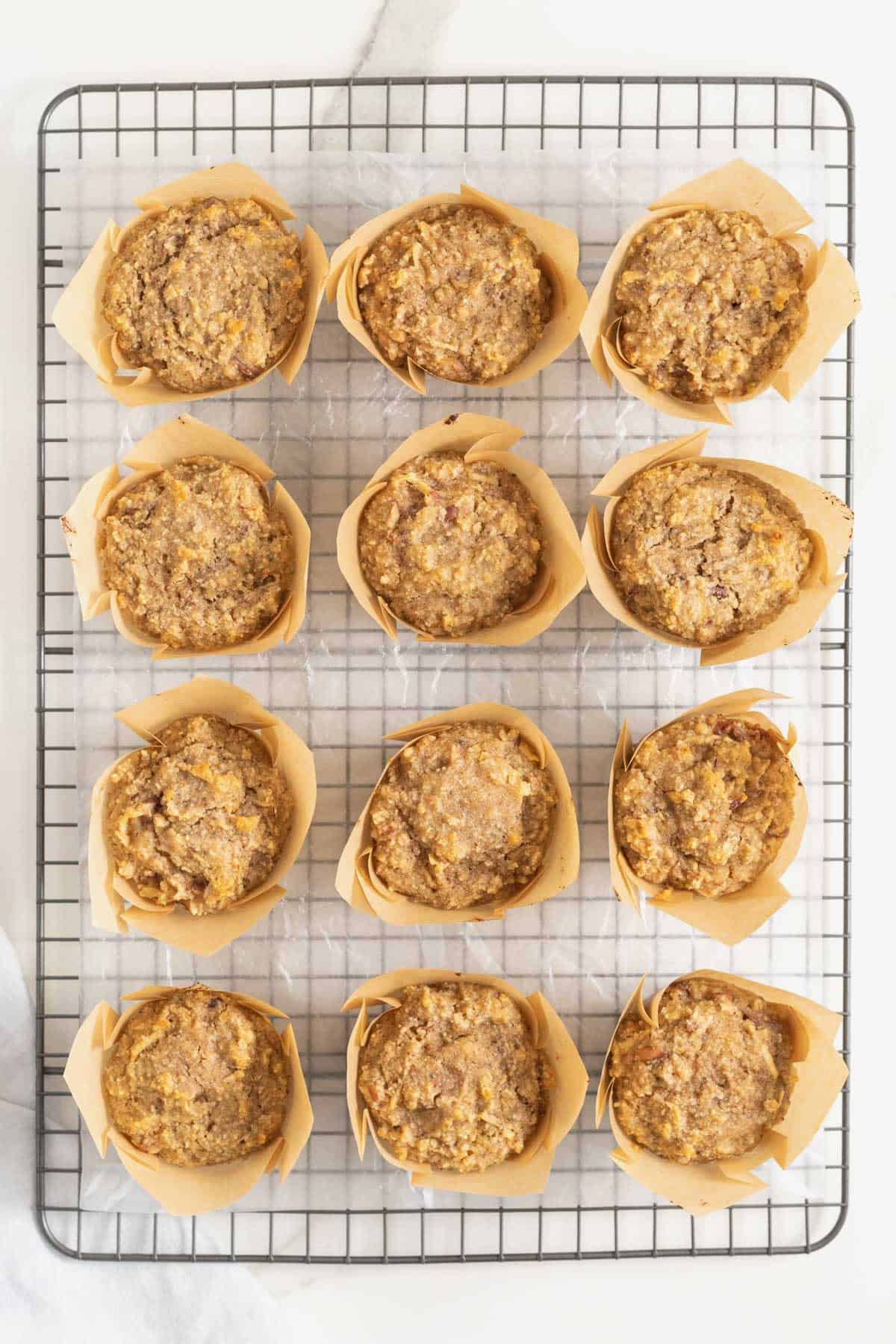 12 superfood muffins in brown paper wrappers on a metal cooling rack.