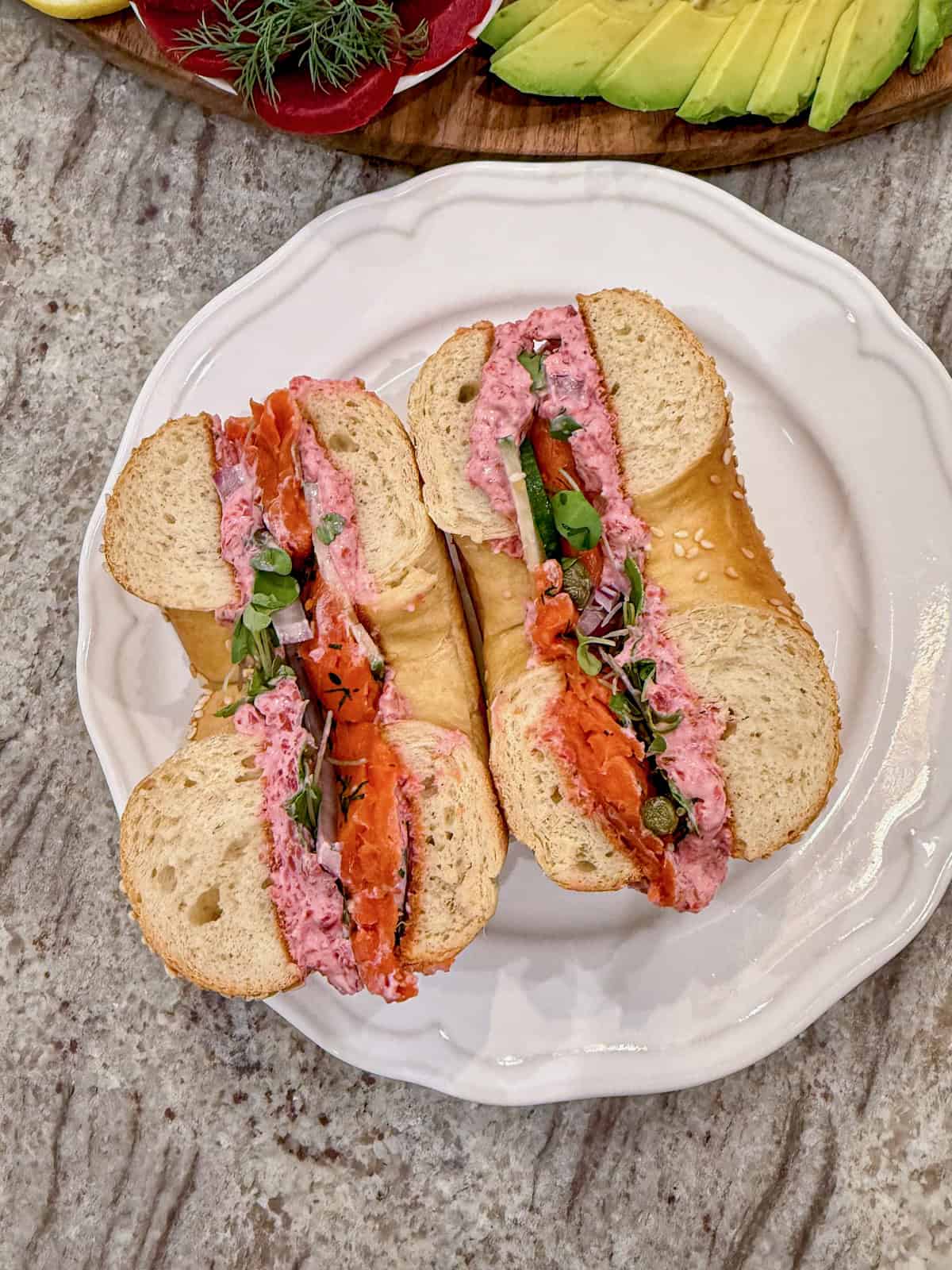 A bagel sandwich cut in half on a white plate.