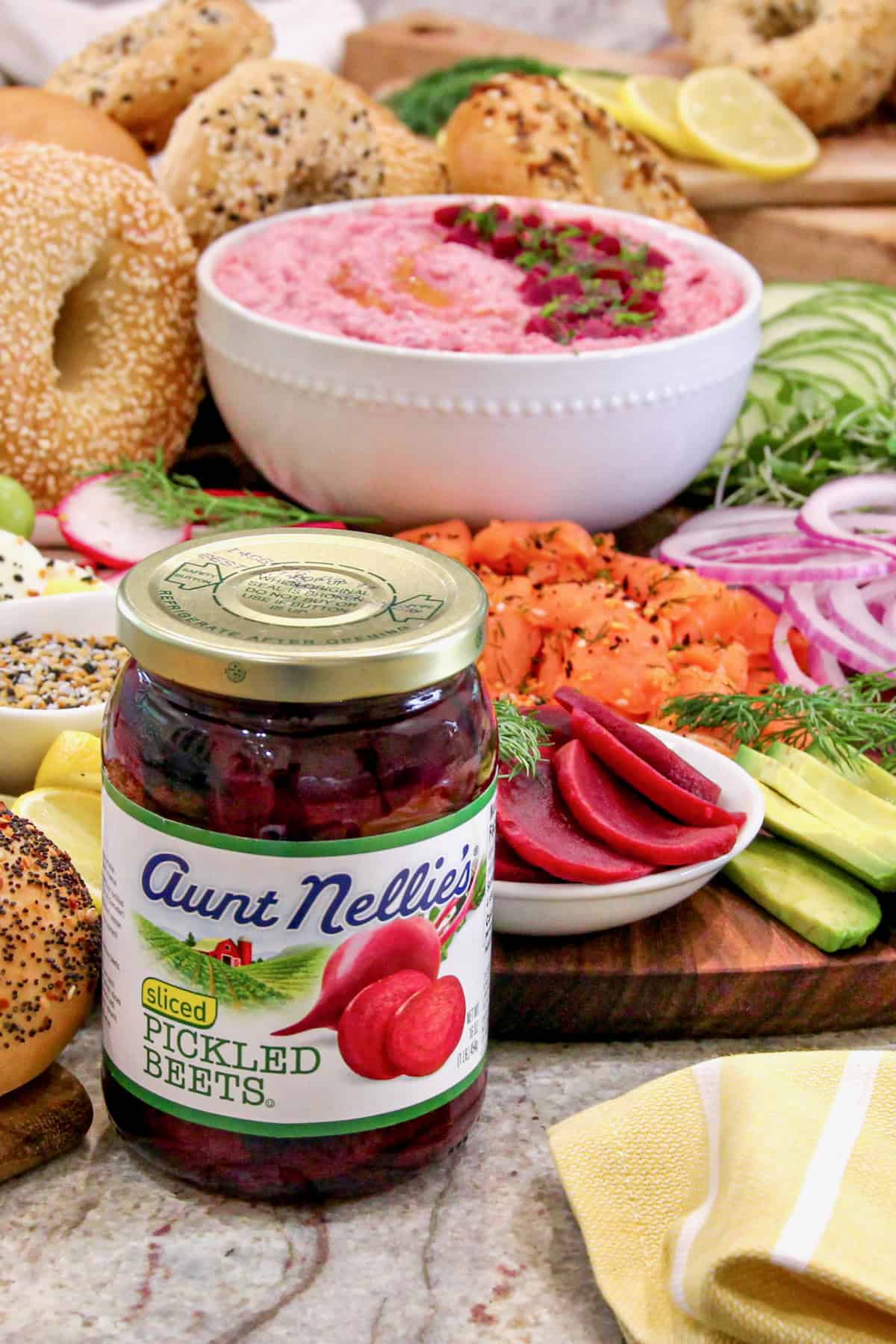 A jar of picked beets in front of a breakfast sandwich bagel board.