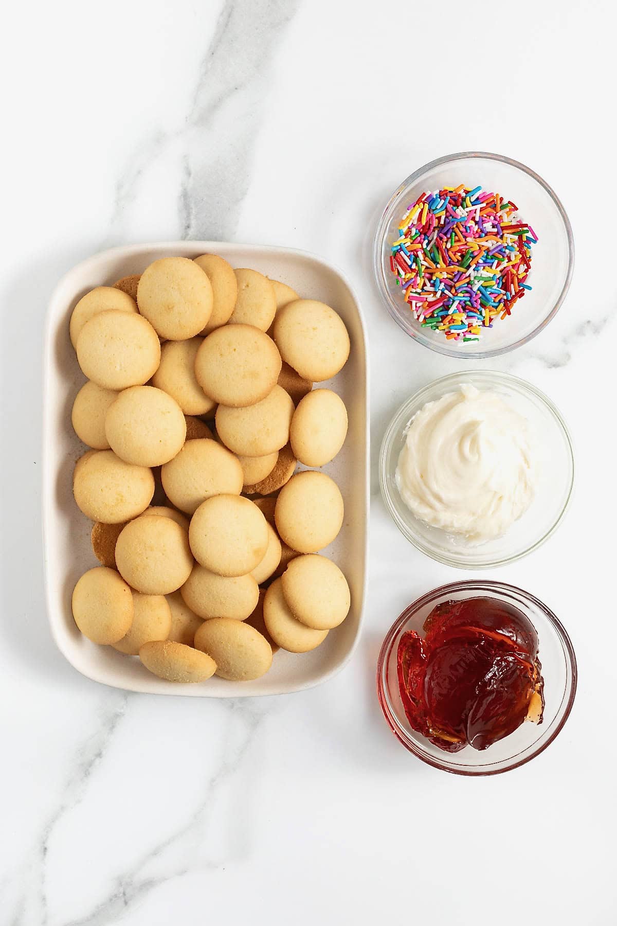 Ingredients to make Nilla wafer pop tarts in small dishes on a white marble counter.