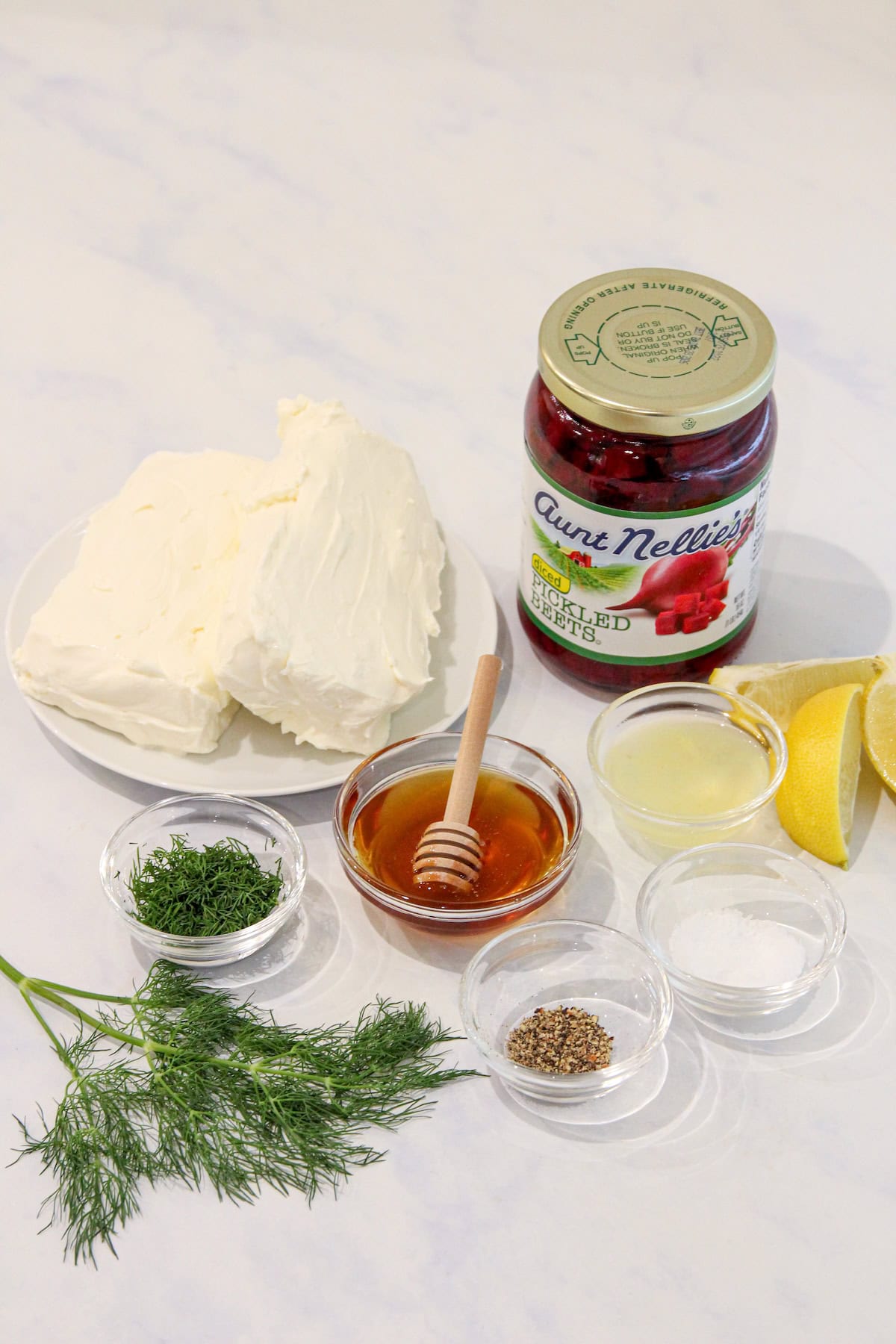 Ingredients to make beet cream cheese spread on a white marble counter.