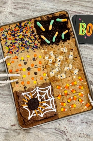 Halloween cookie bars in a sheet pan on a gray and white marble counter.