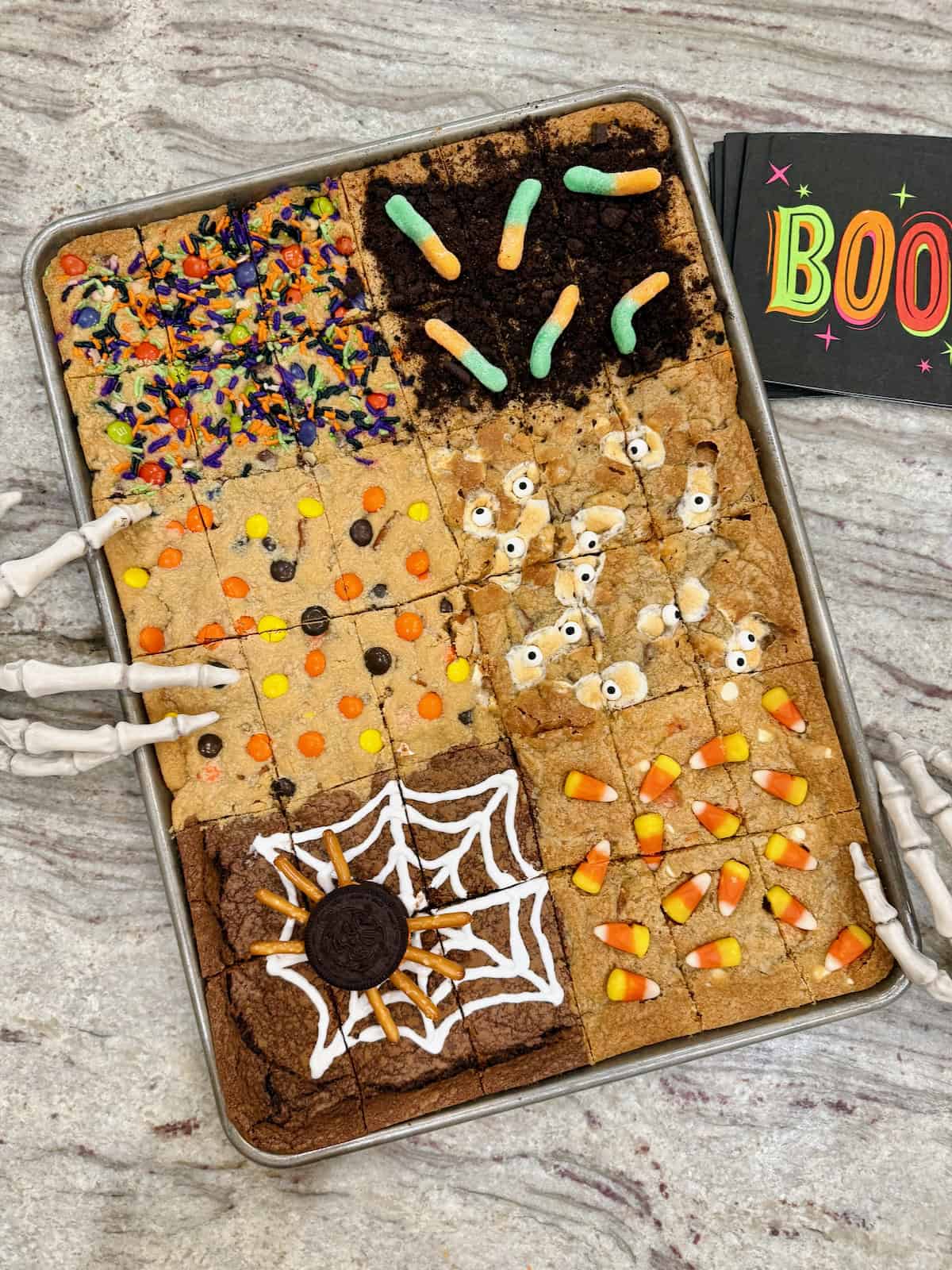 Halloween cookie bars in a sheet pan on a gray and white marble counter.