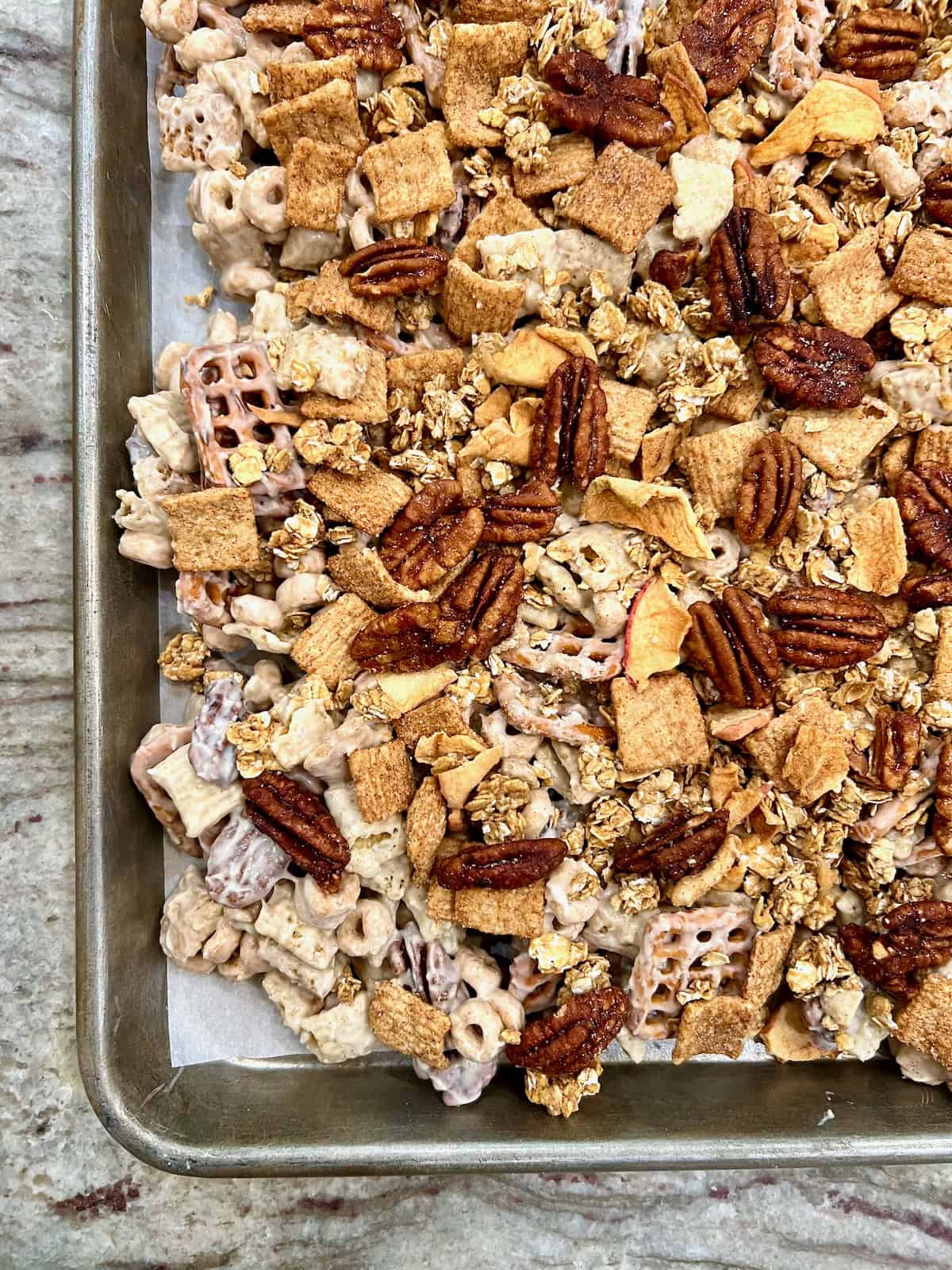 Apple pie snack mix on a parchment lined baking sheet.