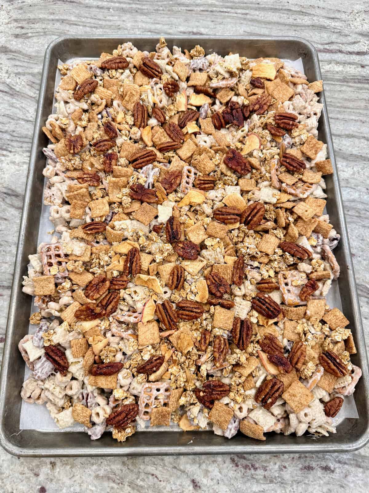 Apple pie snack mix on a parchment lined baking sheet.