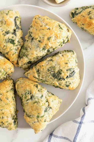 A round white serving platter of spinach artichoke scones.