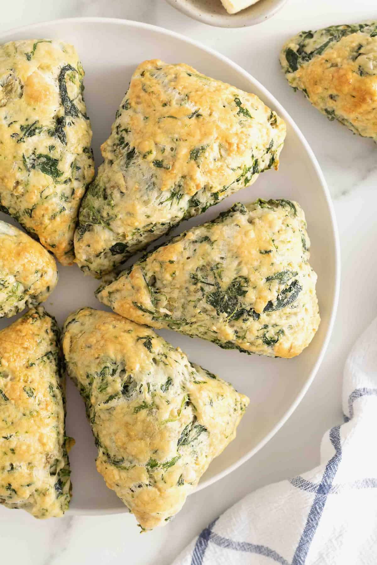 A round white serving platter of spinach artichoke scones.