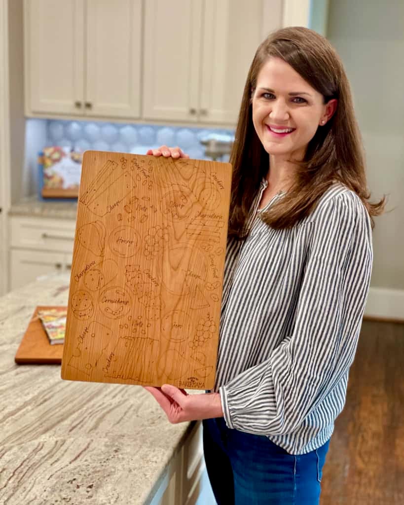 Maegan Brown holding her signature board while standing in her kitchen.
