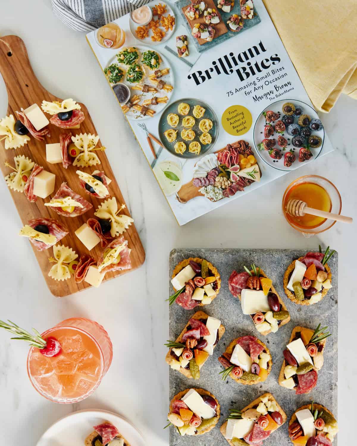 A wooden serving board of Bow-tie Antipasto Bites on a white counter.