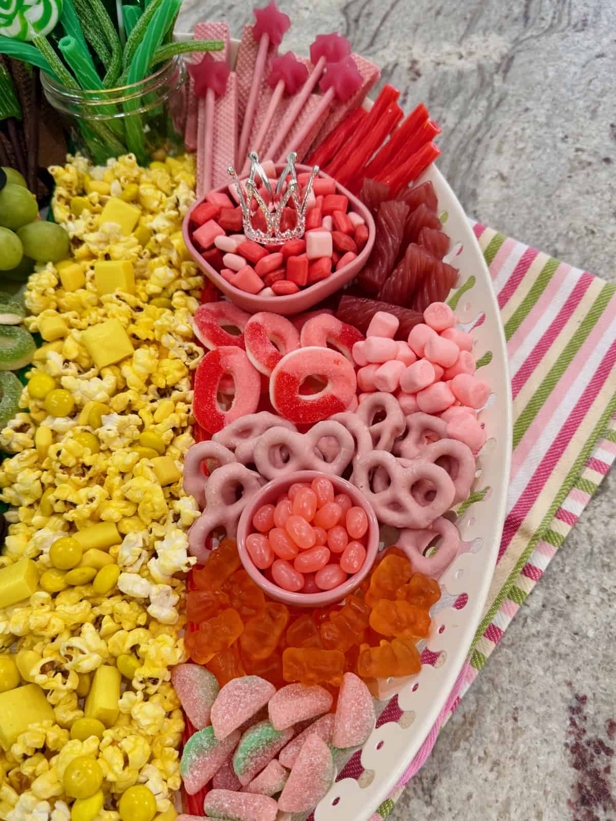 Pink candies, pink yogurt covered pretzels and wafer cookies on the right side of a white platter.