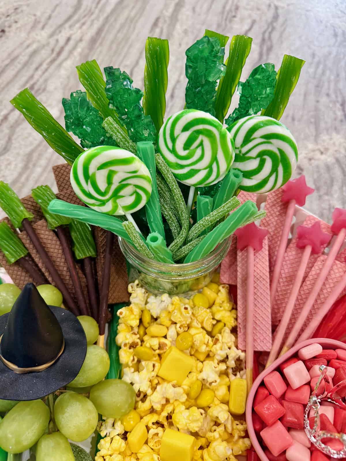 Green lollipops and sour candy sticks in amazon jar.