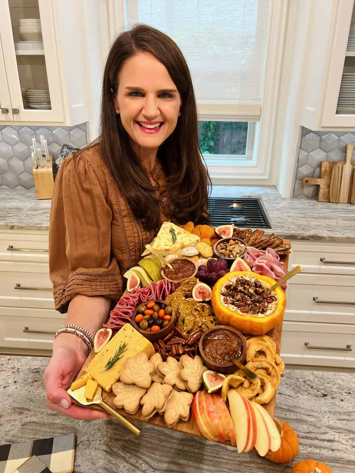 Maegan Brown wearing a brown three quarter length sleeved blouse holding her fall signature board.
