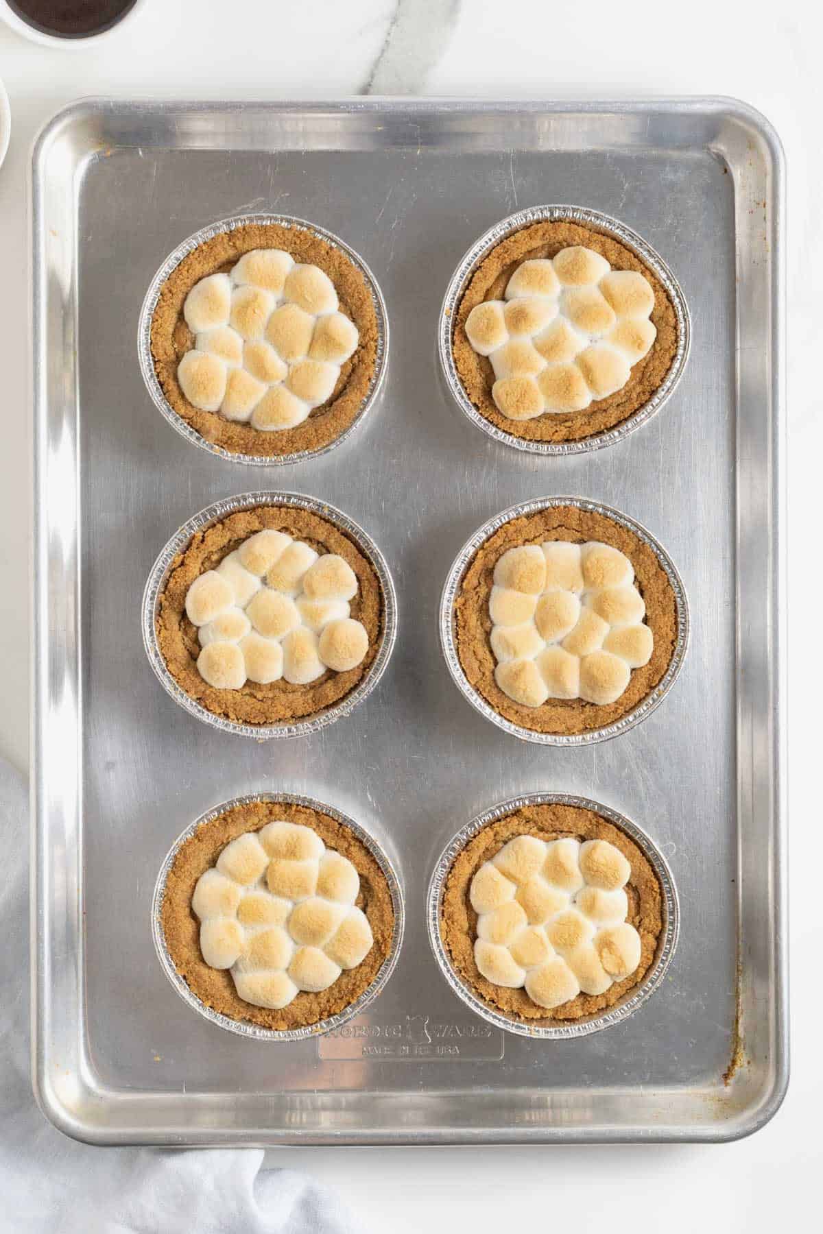 Marshmallows melted on mini s'mores cookie pies.