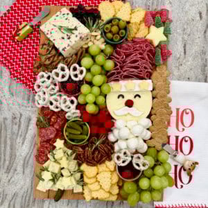 A Christmas charcuterie board with a Santa made out of salami and cheeses, as well as other festive touches.